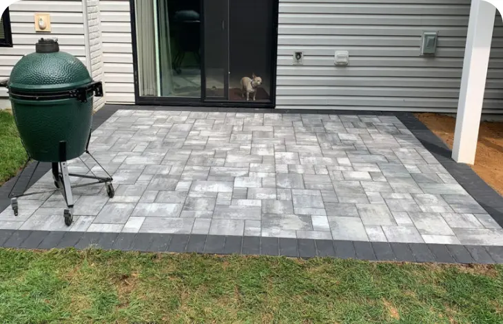 Newly installed gray stone patio in backyard with sliding glass door.